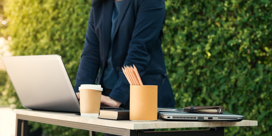 Man werkt op laptop aan tuintafel.